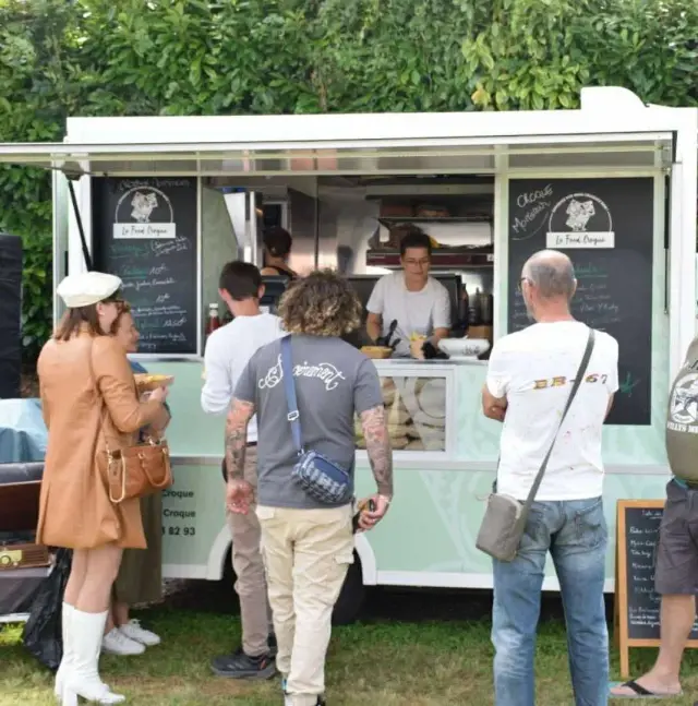 Le camion du Food Croque ouvert sur la pelouse, les clients devant le comptoir et l’ardoise du jour