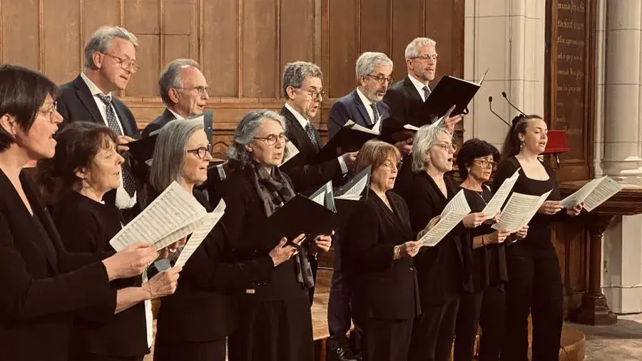 Chorale en tenue noire, partitions en main, chantant dans l'église de Saint-Denis-le-Ferment devant les boiseries.