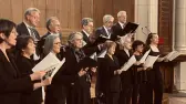 Chorale en tenue noire, partitions en main, chantant dans l'église de Saint-Denis-le-Ferment devant les boiseries.