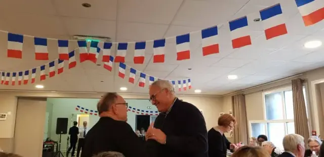 Salle décorée de guirlandes tricolores, personnes attablées