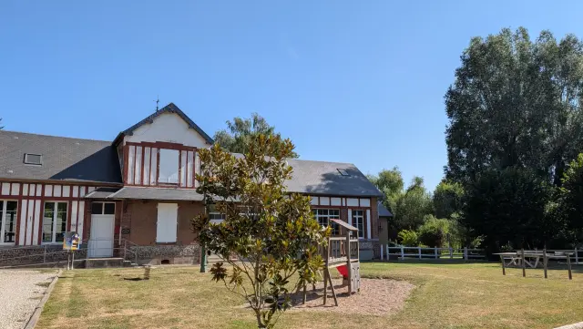 Le bâtiment à colombages de l'école et sa cour arborée