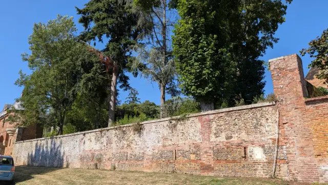 Long mur ancien en brique et silex bordant la route