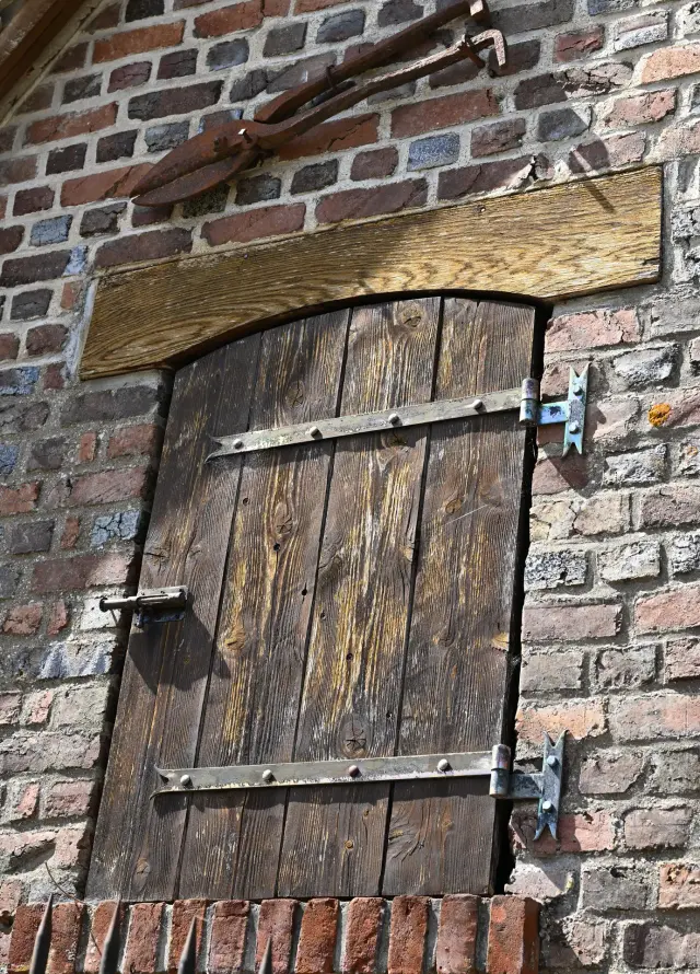 Porte en bois dans un mur de brique, outils anciens accrochés