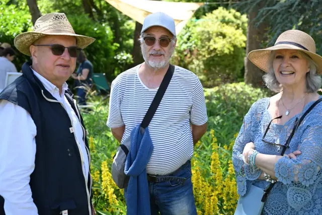 Trois visiteurs souriants dans un jardin fleuri